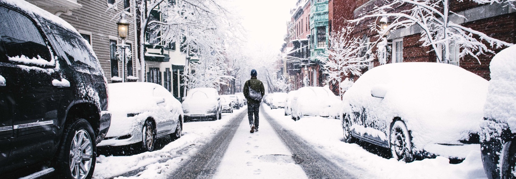 person walking down snow covered Boston street 