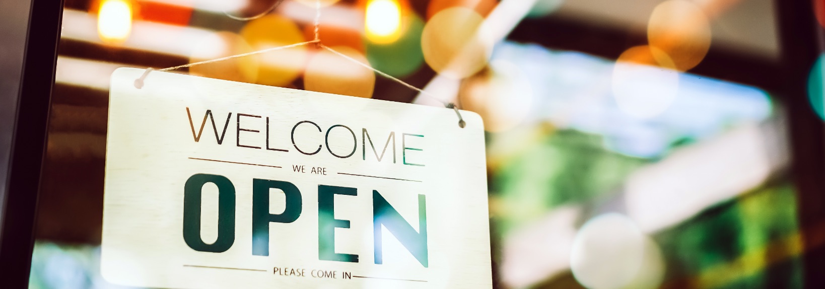 Welcome/Open sign on glass door with colorful reflections